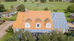 Aerial photo of a roof replacement with bare decking shown with an empty pasture in the background - Roofing Companies in College Station Sustainable Roofing
