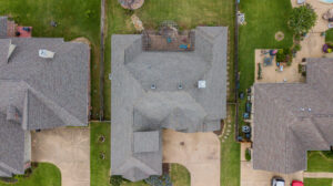 Direct overhead photo of a home sandwiched between other homes in a local subdivision with a new replacement roof in weathered wood colored by College Station Roofer - Sustainable Roofing LLC