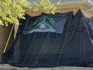Upgraded landscape protection for a home in the process of replacing their roof in the Brazos Valley using a black tarp and a Sustainable Roofing logo'd banner by College Station Roofing Company
