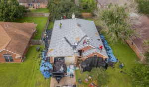 Overhead progress photo roof with a leak proof barrier already installed by the roofing contractors standing on the roof as the house is surrounded by blue tarp to prevent debris from getting in the yard and provided by roofer in college station, Sustainable Roofing