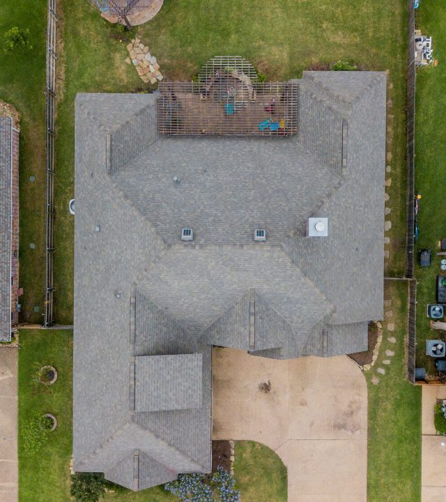 Direct overhead photo of a home sandwiched between other homes in a local subdivision with a new replacement roof in weathered wood colored by College Station Roofer - Sustainable Roofing LLC