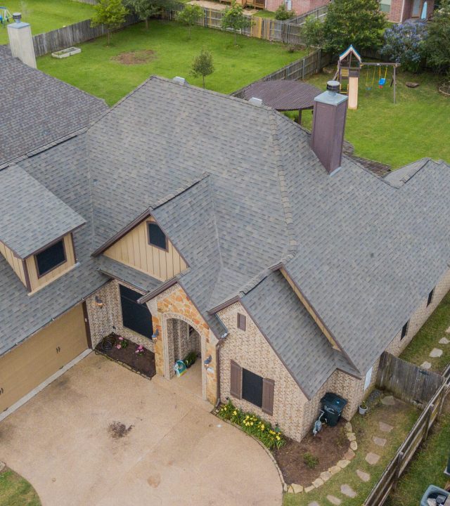 Overhead view of a home with a new roof replacement with malarkey highlander shingles in a color of weathered wood - College station Roofing companies Sustainable Roofing LLC